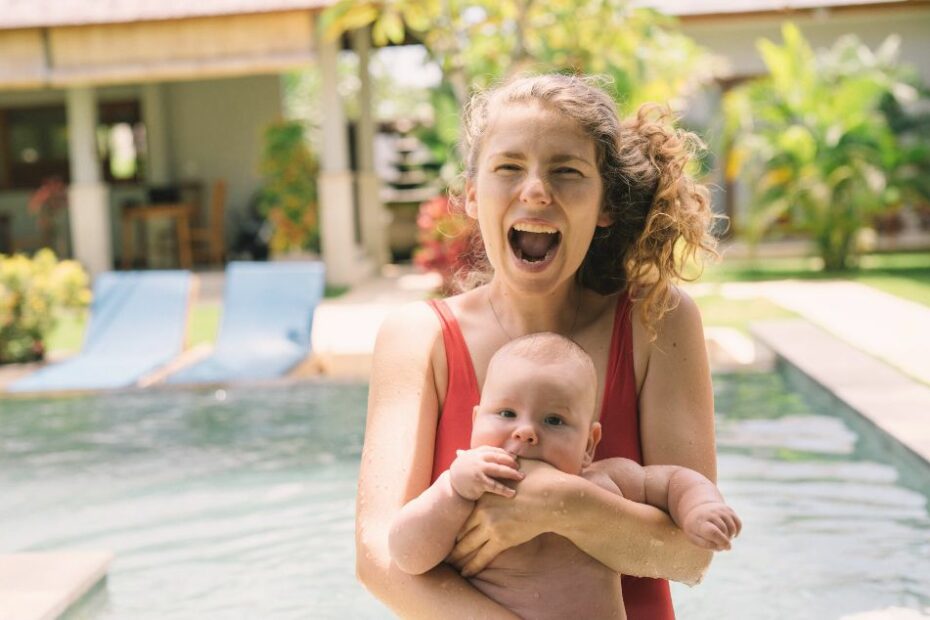 Parents souriants tenant leur jeune enfant dans les bras lors d'une promenade pour voyager avec un bebe sereinement