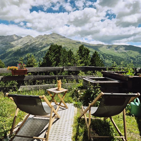 Deux transats sur une terrasse fleurie face aux montagnes